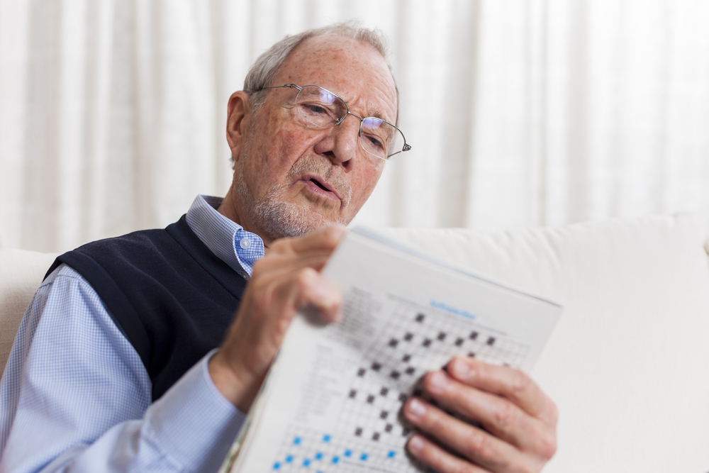 stay occupied senior living senior man doing crossword puzzle in newspaper