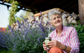 Senior woman sitting on front porch steps with glass of water enjoying the outdoors