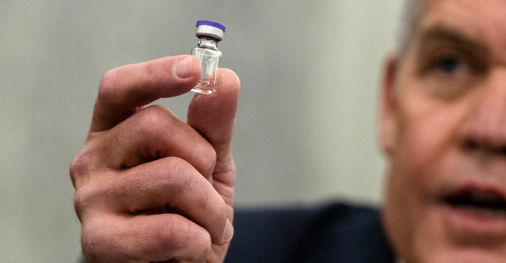 Close up of man holding small container with vaccine