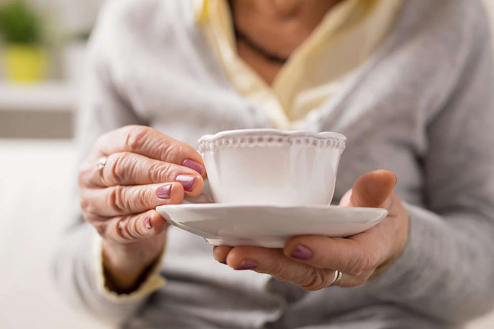 Woman sitting with cup of tea in hand on a saucer