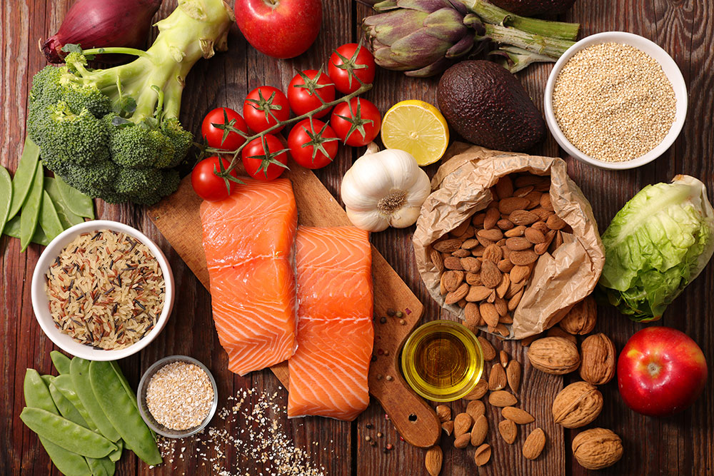 Board with healthy foods spread out on it from salmon to nuts, grains, and vegitables