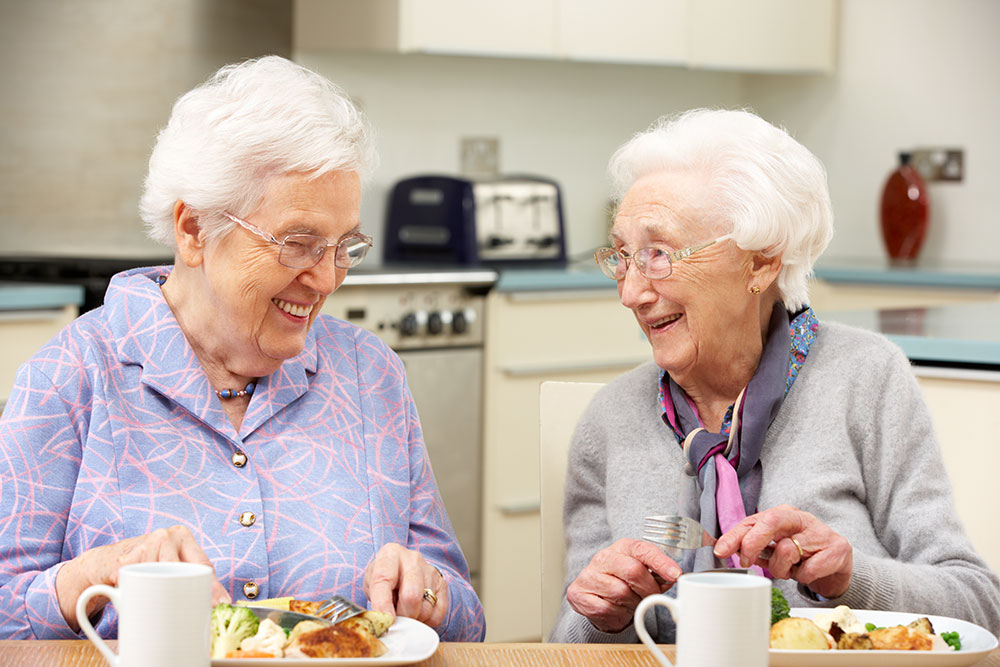 Senior women in assisted living eating dinner together