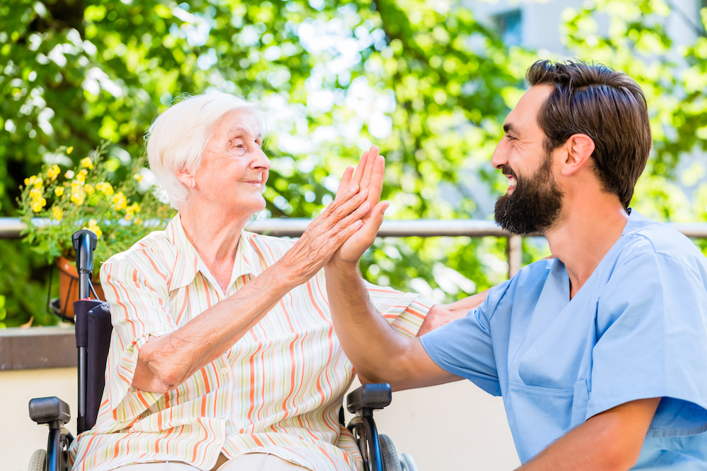 A caregiver and a senior woman high five