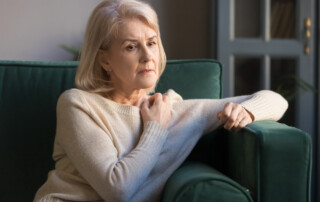 A senior woman sits on her sofa alone and anxious
