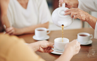 A senior woman pours tea into cups