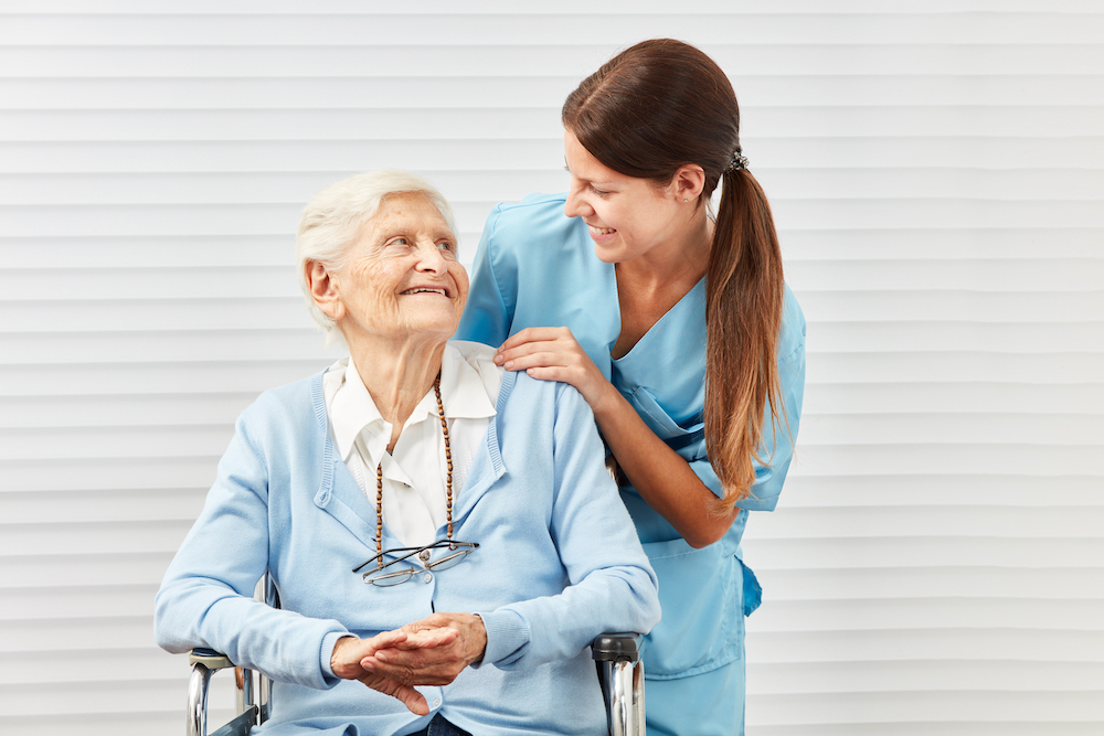 A dementia care patient and a nurse smile and talk