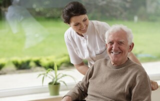 A caregiver helps a senior man at the assisted living apartments
