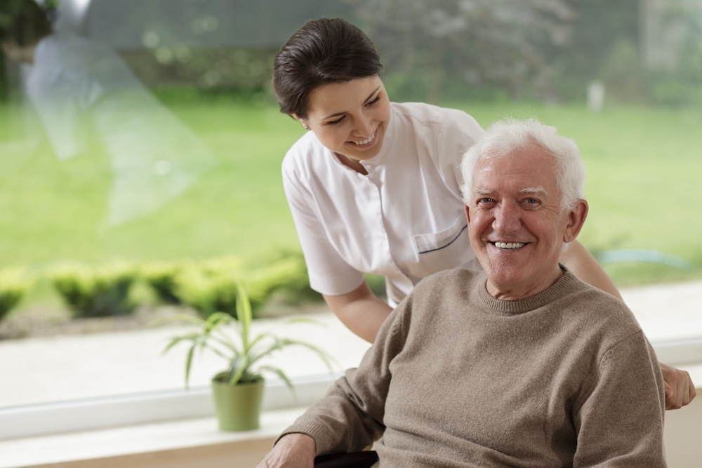 A caregiver helps a senior man at the assisted living apartments