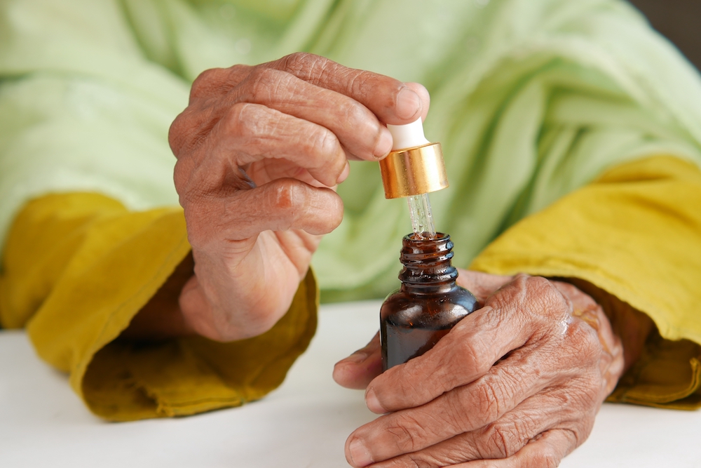 A senior woman who lives at assisted living apartments applying essential oils on her hand