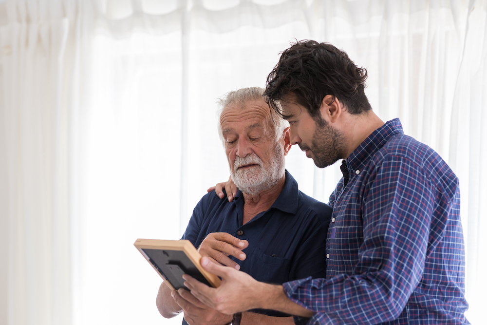 A man shows his senior father a photograph